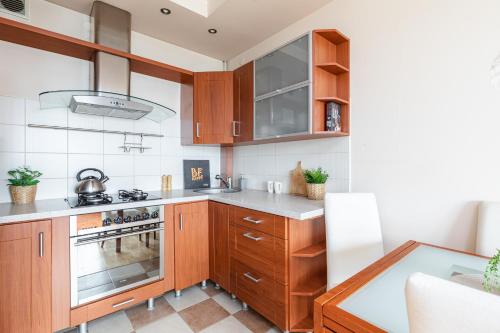 a kitchen with wooden cabinets and a stove at SuperApart Dzieci Warszawy 27a in Warsaw