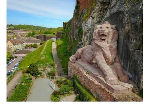 uma estátua de um leão sentado ao lado de uma parede em Maison entre ville et montagne em Valdoie