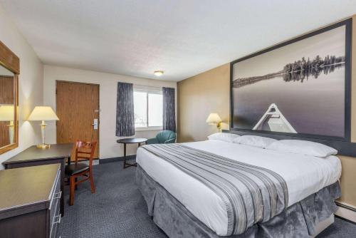 ein Hotelzimmer mit einem großen Bett und einem Schreibtisch in der Unterkunft Super 8 by Wyndham Guelph in Guelph