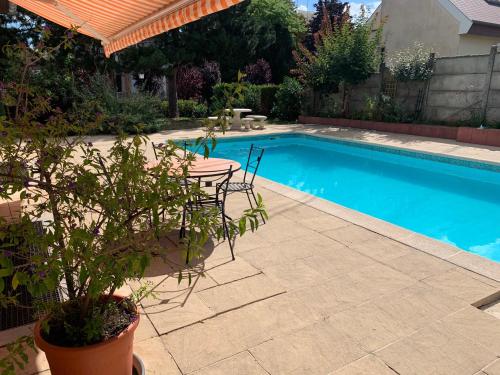 un patio con mesa y sillas junto a una piscina en GITE CENTRE ALSACE, en Barr