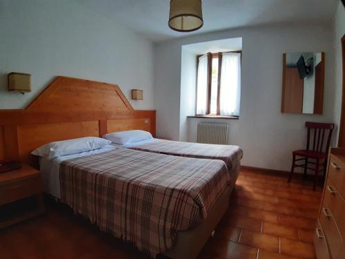 Schlafzimmer mit einem Bett mit einem Kopfteil aus Holz und einem Fenster in der Unterkunft Hotel Paganella in Molveno