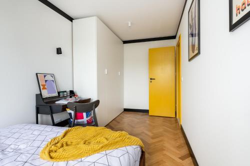 sypialnia z łóżkiem i biurkiem z żółtymi drzwiami w obiekcie Modernizmo by 3City Rentals w mieście Gdynia