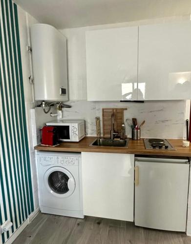 une cuisine avec des armoires blanches et une machine à laver dans l'établissement Bright studio with balcony at the foot of the sea, à Nice