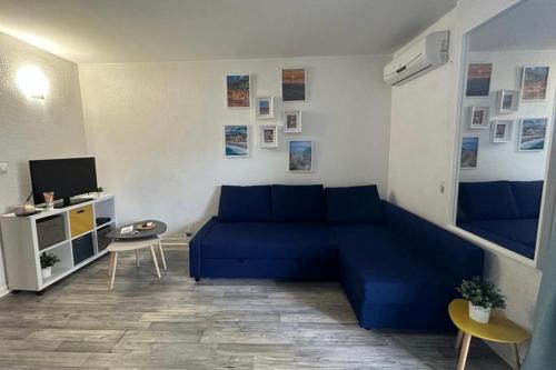un salon avec un canapé bleu et une télévision dans l'établissement Bright studio with balcony at the foot of the sea, à Nice