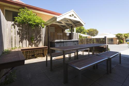 una mesa de picnic y bancos en un patio en Port Campbell Parkview Motel & Apartments, en Port Campbell