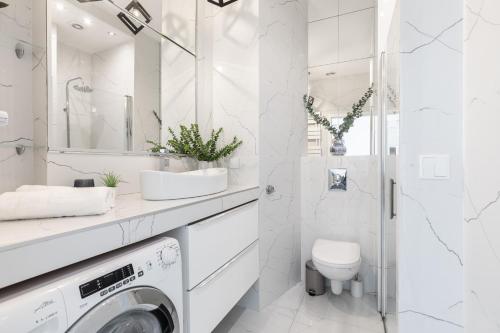 a white bathroom with a washer and dryer at SuperApart Chmielna 73A, City Center in Warsaw