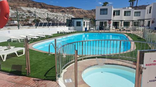 una piscina en un hotel con mesas y sillas en Bungalows Boston, en Puerto Rico de Gran Canaria