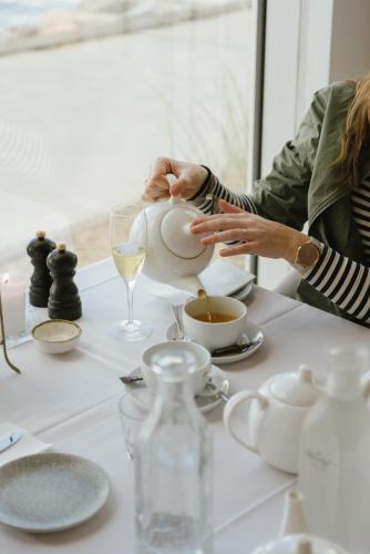 a woman pouring tea into a teapot on a table at Marienlyst Strandhotel in Helsingør