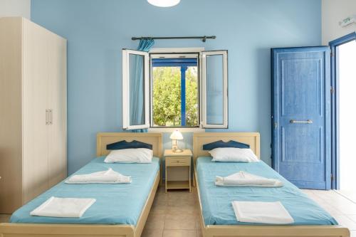 two beds in a room with a window at Studios Ninemia Serifos 3 in Livadi