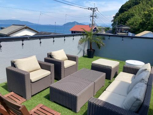 eine Terrasse mit Korbstühlen sowie einem Tisch und Stühlen in der Unterkunft ロハスResort宮浦 in Fukuoka