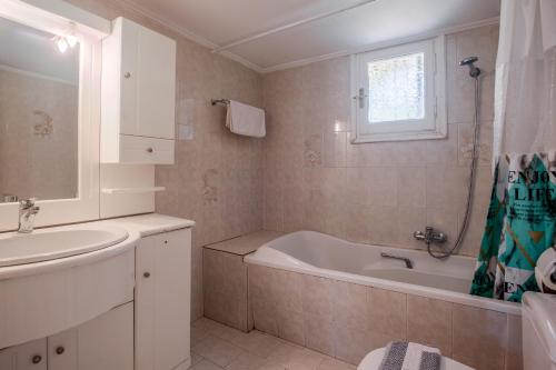 y baño con bañera y lavamanos. en Anastasios Holiday Home, en Gazátika