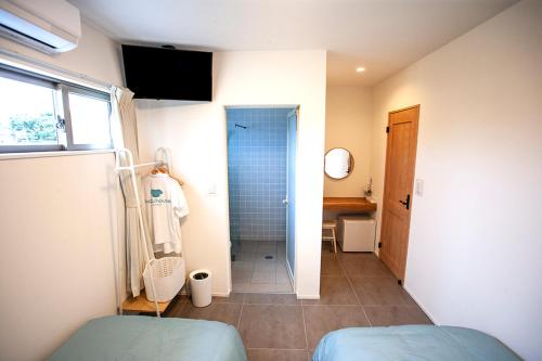 een badkamer met een douche, een toilet en een wastafel bij Hichu House ハイチューハウス in Nago