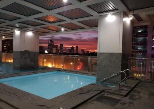 a swimming pool in a building with a view of a city at ADB Avenue Tower Ortigas Manila in Manila