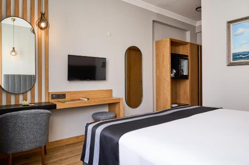 a hotel room with a bed and a desk and a tv at Buyuk Truva Hotel in Canakkale