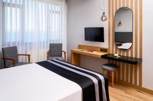 a hotel room with a bed and a desk and a mirror at Buyuk Truva Hotel in Canakkale