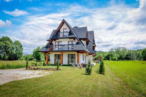 a house with a black roof on a green field at Cicha Woda 300 m od Gorący Potok i Termy Szaflary in Szaflary