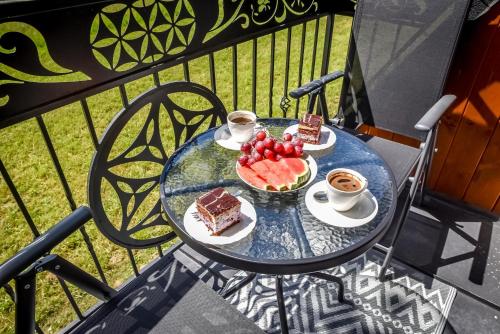 a table with cake and fruit and coffee on a balcony at Cicha Woda 300 m od Gorący Potok i Termy Szaflary in Szaflary