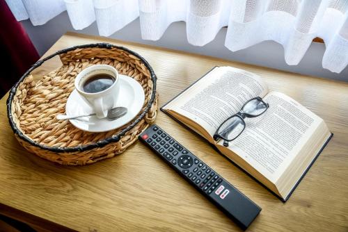 a cup of coffee and a book and a remote control at Cicha Woda 300 m od Gorący Potok i Termy Szaflary in Szaflary