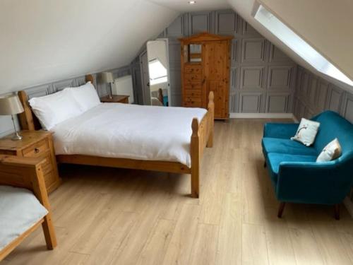 a bedroom with a bed and a blue chair at Newhall Cottage in Bressay