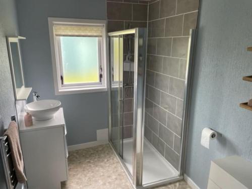 a bathroom with a glass shower and a sink at Newhall Cottage in Bressay