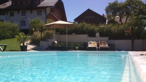 a swimming pool with two chairs and an umbrella at Gesundheitshof Lohninger in Mondsee