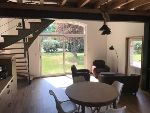 a living room with a table and chairs and a staircase at Ferme Boisquillon in Marcilly-en-Gault