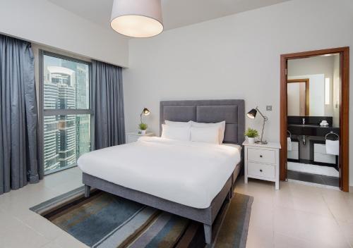 a bedroom with a large bed and a large window at Nasma Luxury Stays - Central Park Tower in Dubai