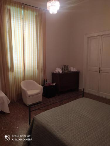 a bedroom with a bed and a chair and a window at Maison Canopée in Messina