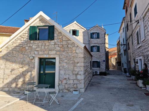 - un bâtiment en pierre avec une porte verte et une chaise dans l'établissement House Riva, à Pirovac