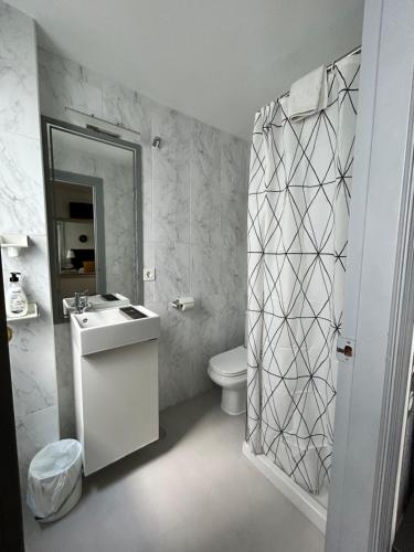 a bathroom with a sink and a toilet and a mirror at Hostal Berlin in Marbella