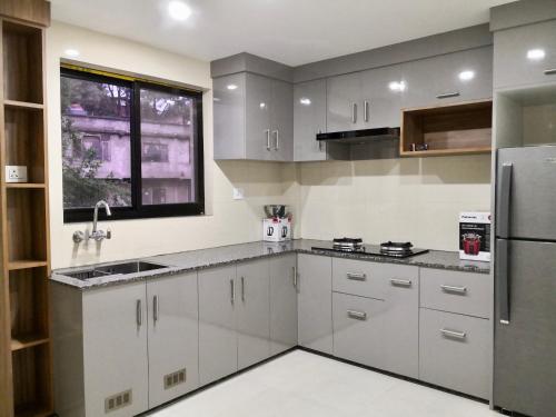 YULOKO GUEST HOUSE في كاتماندو: مطبخ مع دواليب بيضاء وثلاجة ستانلس ستيل