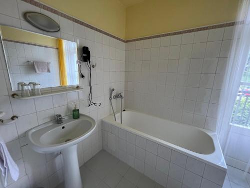 a bathroom with a bath tub and a sink at Hotel Lužná in Luhačovice