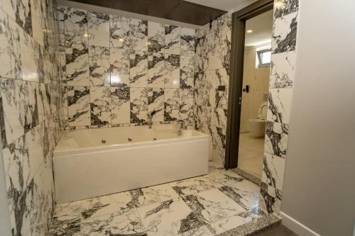 a bathroom with a white tub and marble walls at Newarise Hotel in Rize