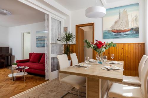 een eetkamer met een tafel en een rode bank bij Garden Vista apartment in Dubrovnik