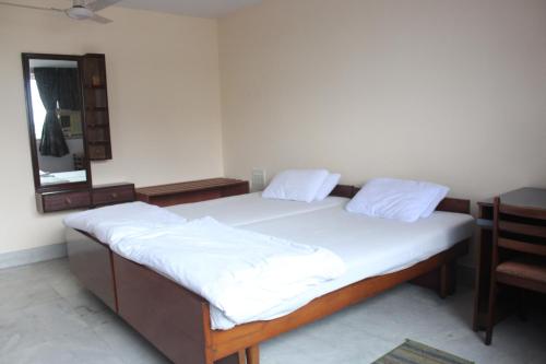 a bedroom with two beds with white sheets and a mirror at Service Apartments, Park Street, Calcutta in Kolkata