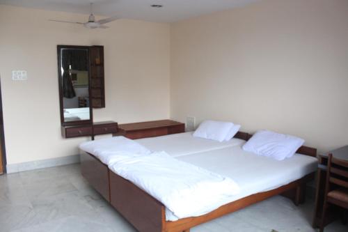 a bedroom with a bed with white sheets and a mirror at Service Apartments, Park Street, Calcutta in Kolkata