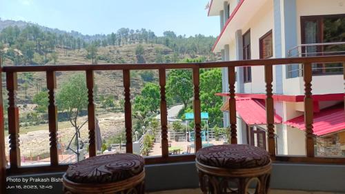 a balcony with two stools and a view of a mountain at Shivalik River Retreat in Almora