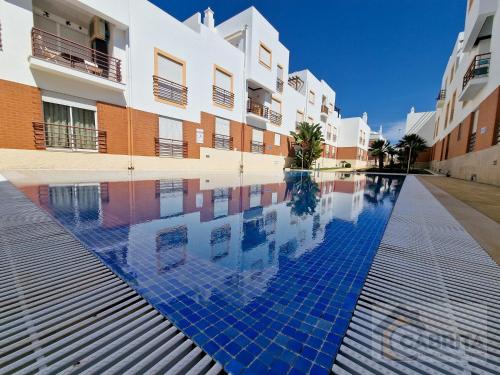 a swimming pool in front of a building at Pé na Areia in Cabanas de Tavira