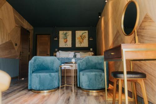 a salon with blue chairs and a table and a mirror at The Garden Rooms in Chathill