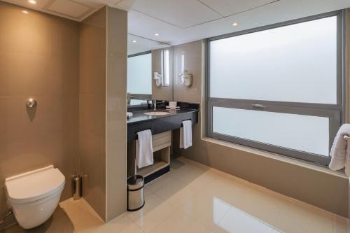 a bathroom with a toilet and a sink and a window at Radisson Blu Hotel, Cairo Heliopolis in Cairo