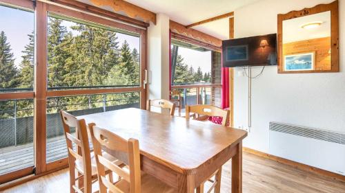 une salle à manger avec une table, des chaises et des fenêtres dans l'établissement V du Bachat Asters E11 - Appt 6 pers, à Chamrousse