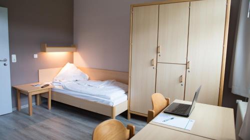 a small room with a bed and a desk with a laptop at DEULA Witzenhausen GmbH in Witzenhausen