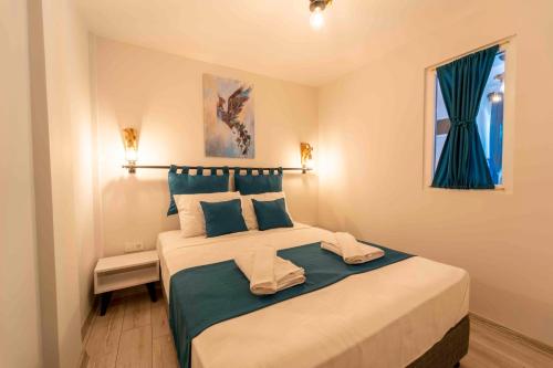 1 dormitorio con 1 cama grande con almohadas azules en Kamkat Otel en Kemer