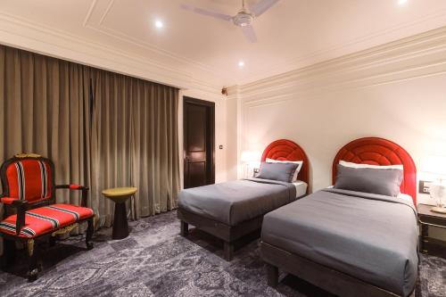 a hotel room with two beds and a chair at The Saga Hotel in New Delhi