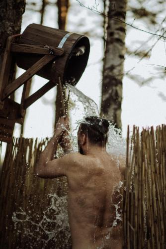 a shirtless man standing in water under a fan at Jurty z widokiem, prywatna balia- DZIKOLAS GLAMPING in Krasnobród
