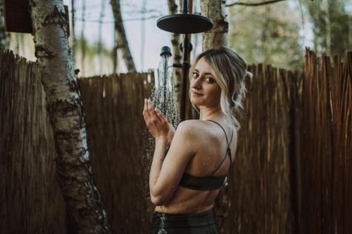 a woman standing in front of a fence at Jurty z widokiem, prywatna balia- DZIKOLAS GLAMPING in Krasnobród