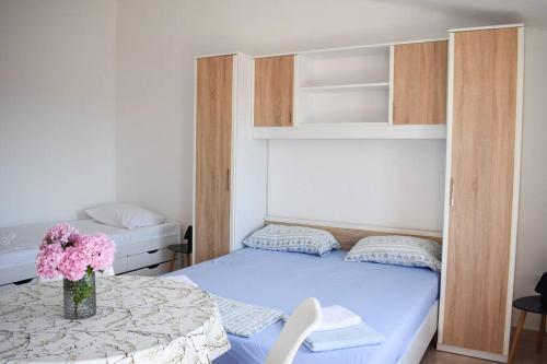 ein kleines Schlafzimmer mit einem Bett und einem Tisch mit Blumen in der Unterkunft Chianti in Pula