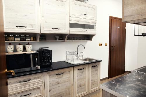 a kitchen with wooden cabinets and a sink and a microwave at Pensiunea Amurg in Odoreu
