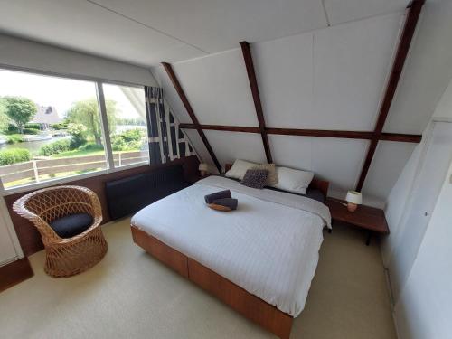 een slaapkamer met een bed en een groot raam bij Marretoer in Uitwellingerga