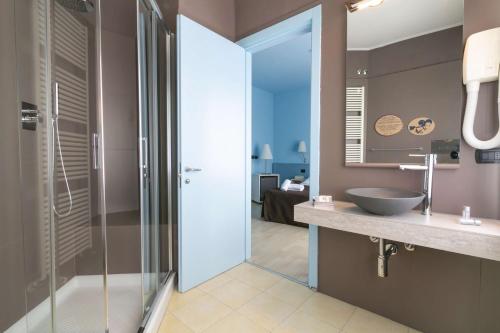 a bathroom with a glass shower and a sink at Hotel Corallo Rimini in Rimini